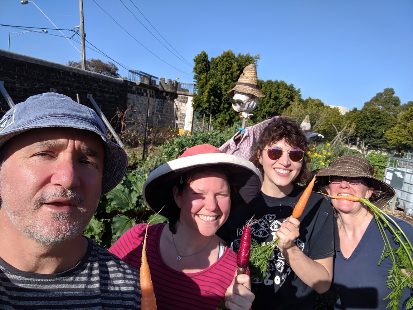 Pentridge Community Garden members holding carrots in front of the bluestone wall